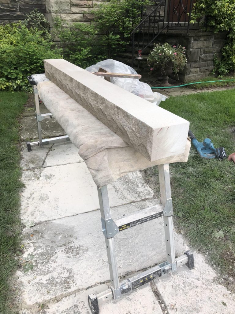 A 5ft long piece of indiana limestone sits on a workbench in a garden.